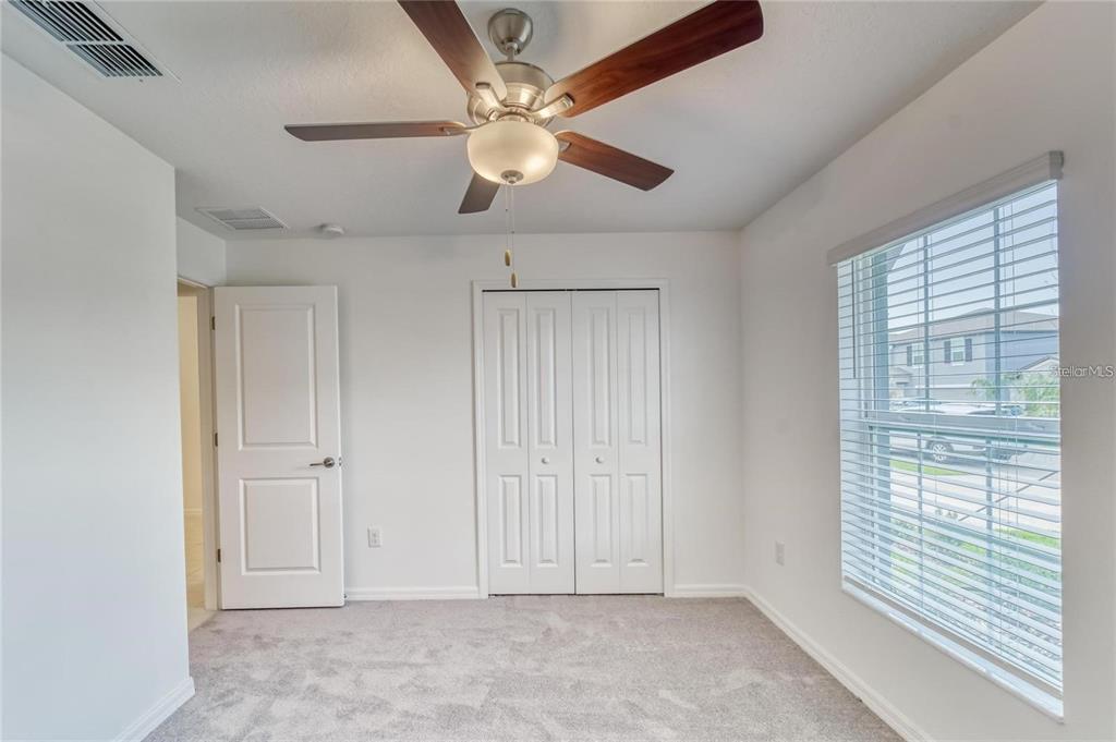 A bedroom features white walls, gray carpeting, a ceiling fan, and a window with blinds — 5514 BLUE AZURE DRIVE, WIMAUMA, FL