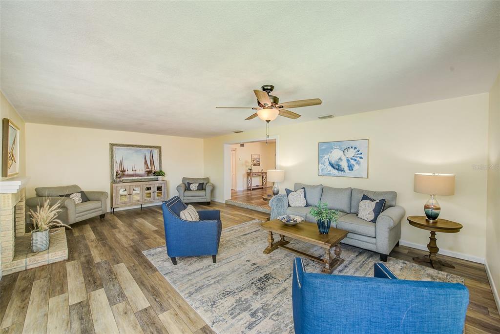 A living room with wood-look flooring, a ceiling fan, a fireplace, and sliding glass doors — 14079 VICTORIA ROAD, LARGO, FL