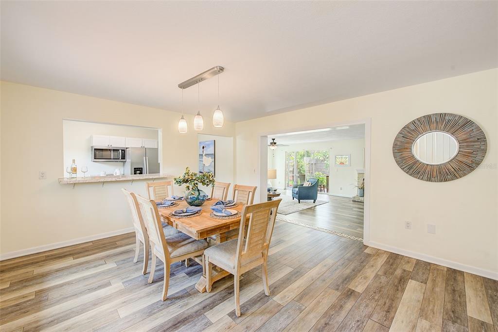 A living room features light-colored walls, wood-look flooring, a ceiling fan, and blue accent chairs — 14079 VICTORIA ROAD, LARGO, FL