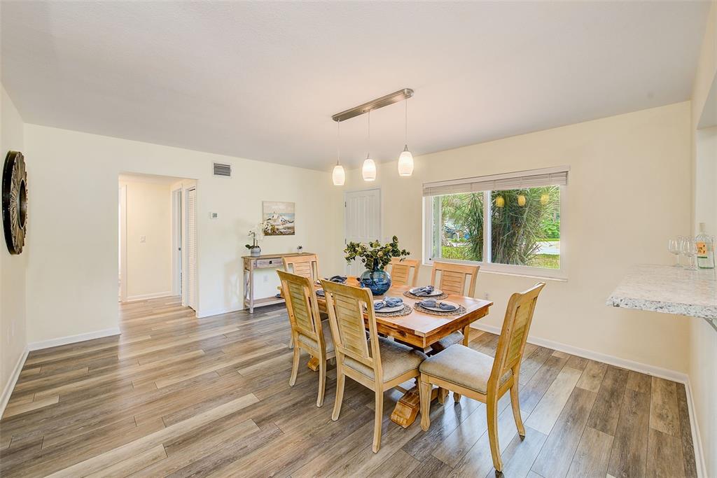 A dining room with a wooden table, light-colored chairs, and wood-look flooring — 14079 VICTORIA ROAD, LARGO, FL