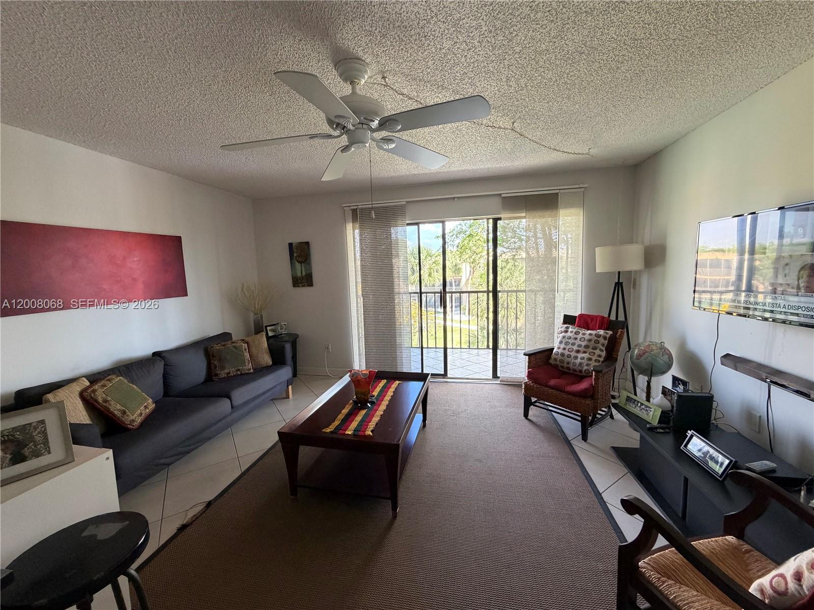 A living room features a dark sofa, a coffee table, and a sliding glass door — 8415 SW 107th Ave # 369W, Miami FL 33173, MIAMI, FL