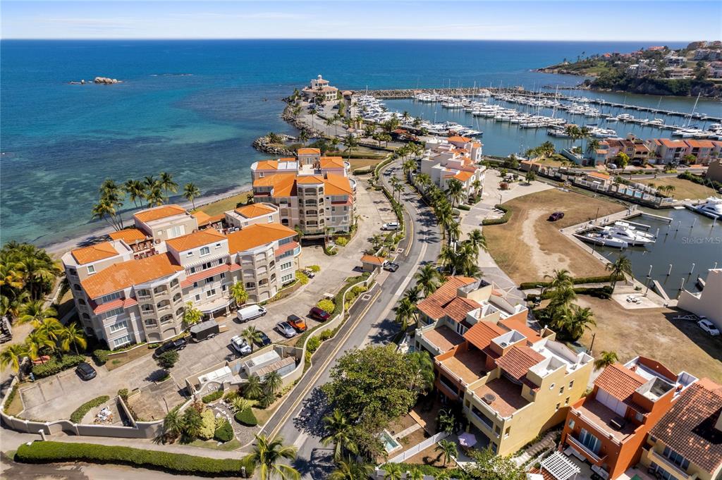 An aerial view shows a coastal residential complex with orange-roofed buildings, a marina, and ocean — 355 HARBOUR DR UNIT 3C - South, HUMACAO, PR