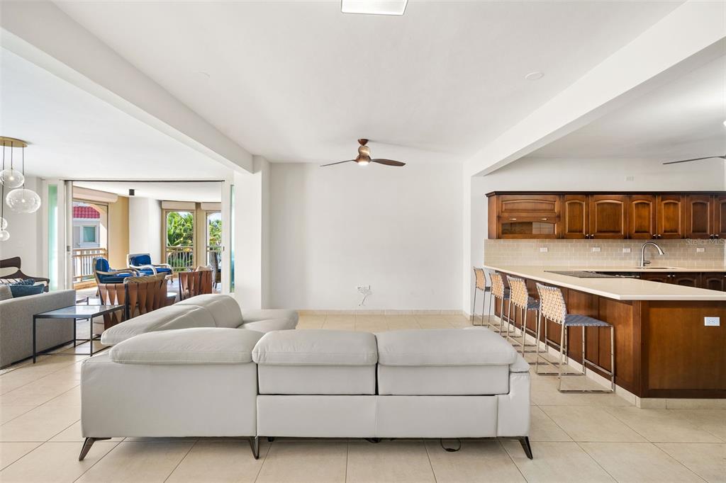 An open-concept living room features a light gray sectional sofa, tile flooring, and a kitchen — 355 HARBOUR DR UNIT 3C - South, HUMACAO, PR