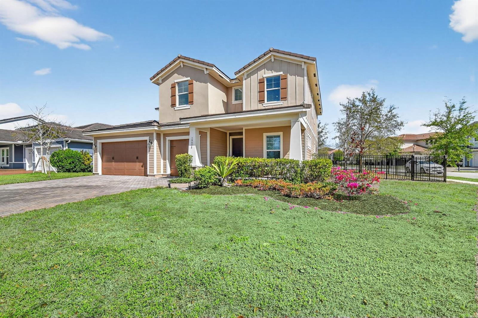 A two-story suburban house with a tan exterior, brown garage doors, and a front lawn — 19535 Split Rail Run, Loxahatchee FL 33470, LOXAHATCHEE, FL