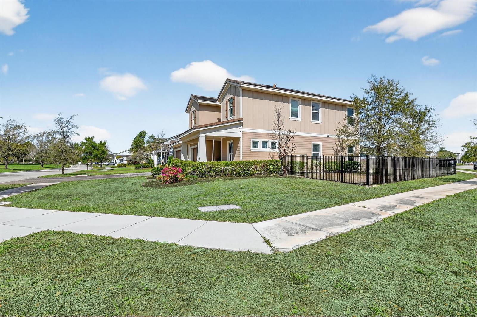 A two-story tan house with a black metal fence sits on a corner lot — 19535 Split Rail Run, Loxahatchee FL 33470, LOXAHATCHEE, FL