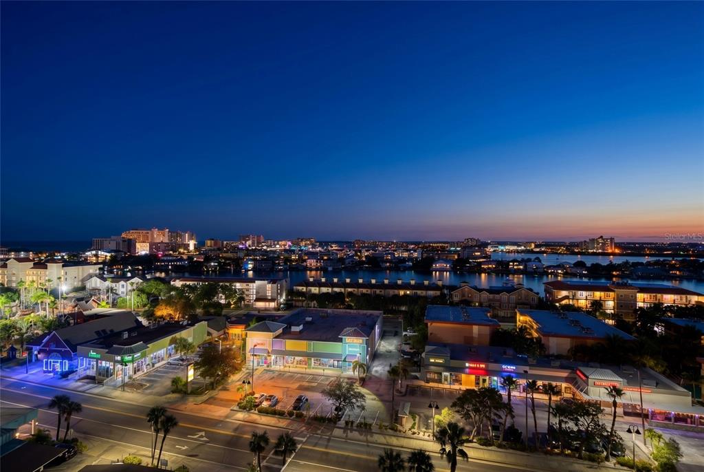 An elevated view of a coastal town at twilight with commercial buildings and waterfront properties — 675 S GULFVIEW BOULEVARD UNIT 1108, CLEARWATER BEACH, FL