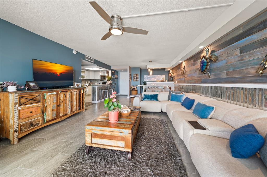 A living room features a rustic wooden console, a sectional sofa, and a wood-paneled wall — 675 S GULFVIEW BOULEVARD UNIT 1108, CLEARWATER BEACH, FL