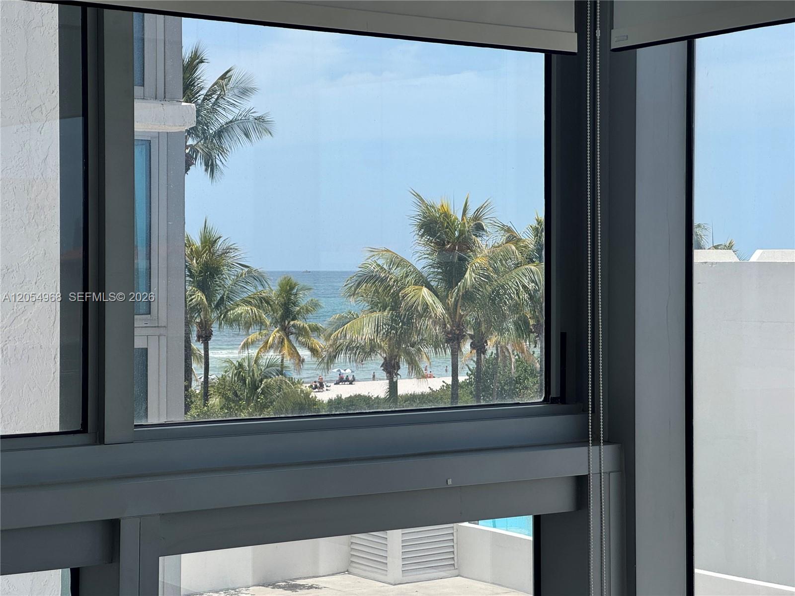 A view of the ocean and beach through a window from inside a room — 2655 Collins Ave # 608, Miami Beach FL 33140, MIAMI BEACH, FL
