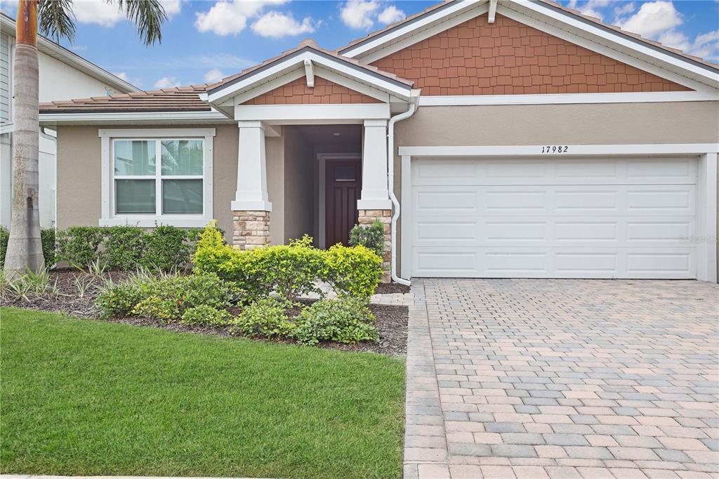 A single-story house features a paved driveway, a two-car garage, and a covered entryway — 17982 GRAND PROSPERITY DRIVE, VENICE, FL