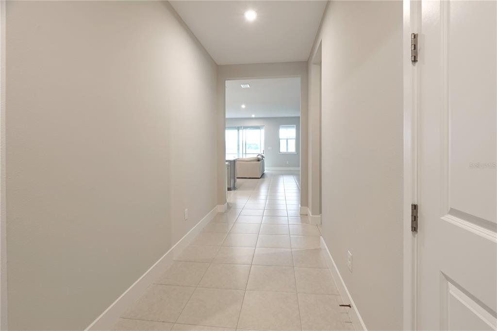 A tiled hallway leads toward an open living area with a sofa and sliding doors — 17982 GRAND PROSPERITY DRIVE, VENICE, FL