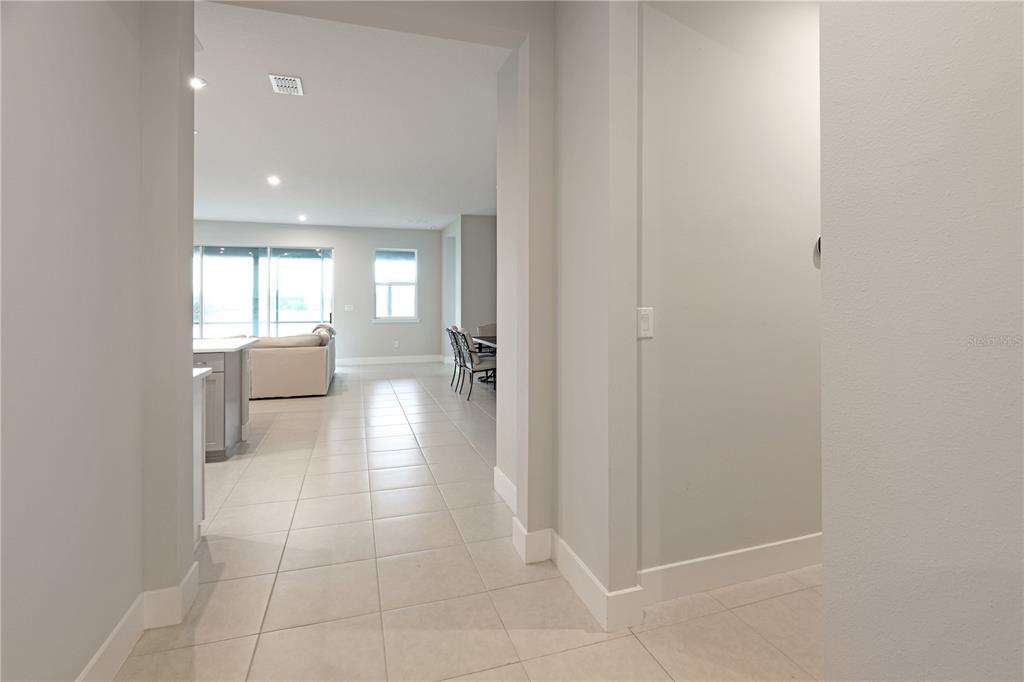 A tiled hallway leads into an open-concept living area with a kitchen and dining space — 17982 GRAND PROSPERITY DRIVE, VENICE, FL