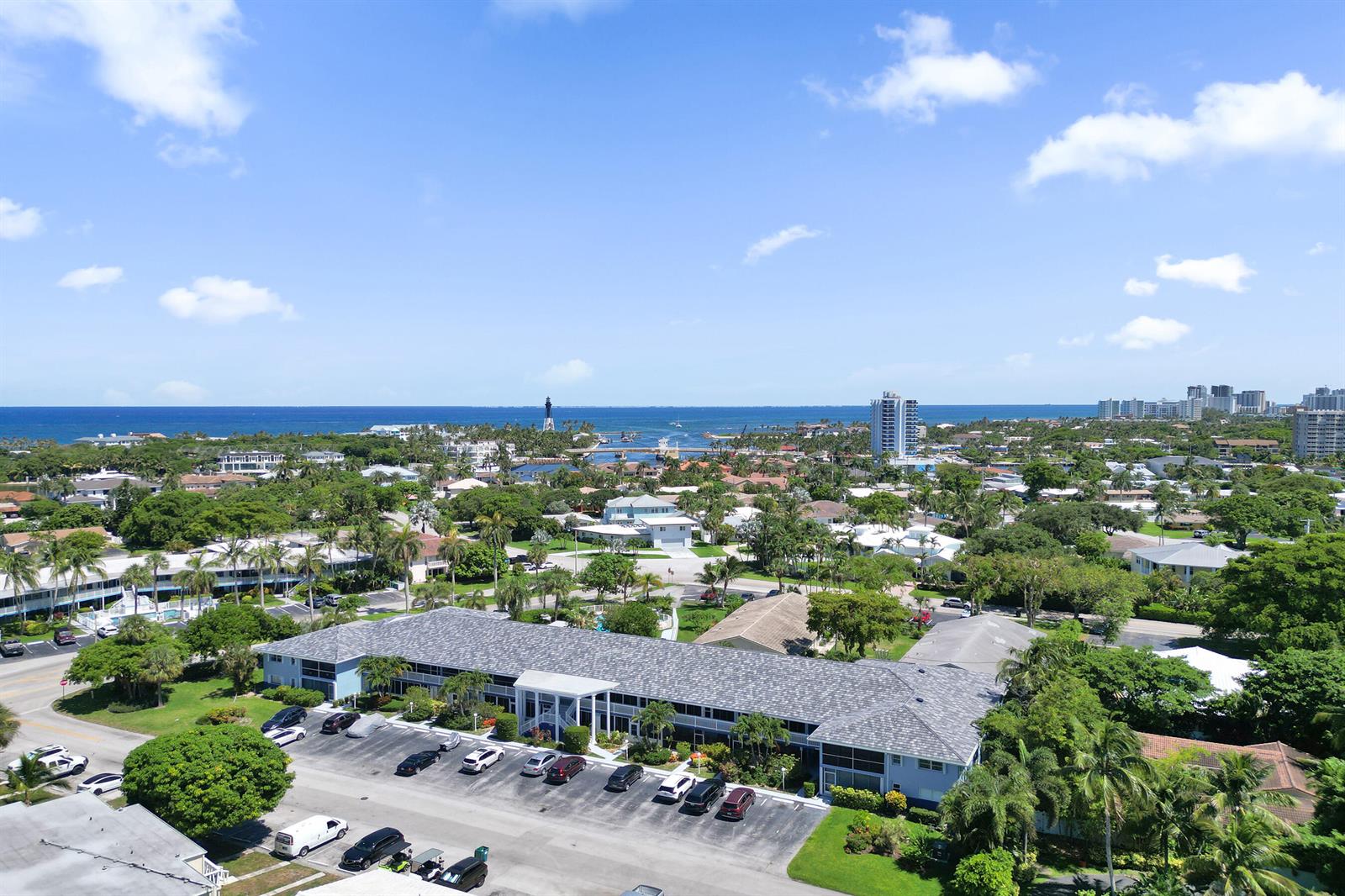 An aerial view shows a multi-story apartment complex with a parking lot and surrounding greenery — 2734 NE 27th Court # 17, Lighthouse Point FL 33064, LIGHTHOUSE POINT, FL