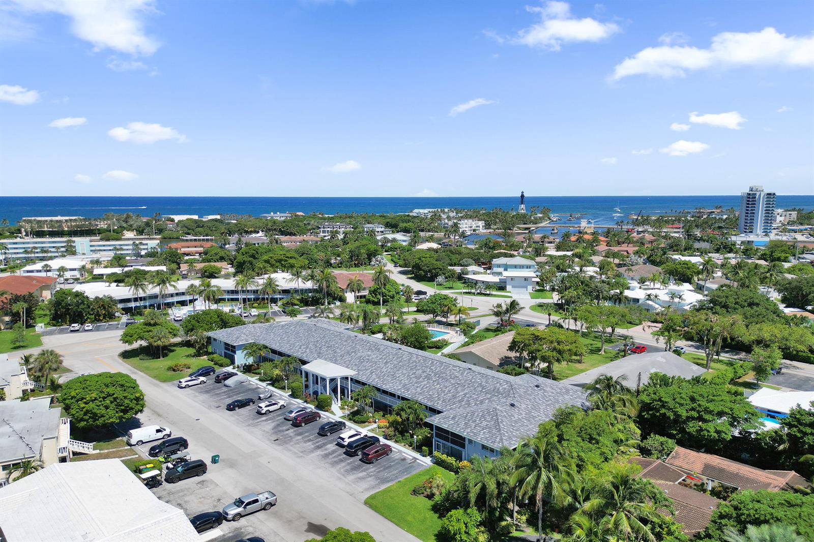 An aerial view shows a multi-story apartment building with a parking lot and surrounding tropical landscaping — 2734 NE 27th Court # 17, Lighthouse Point FL 33064, LIGHTHOUSE POINT, FL