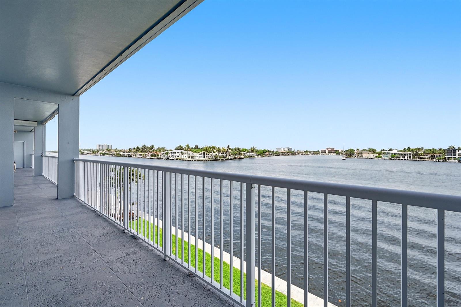 A balcony with a white metal railing overlooks a wide river and distant waterfront homes — 1201 S Riverside Drive # 306, Pompano Beach FL 33062, POMPANO BEACH, FL