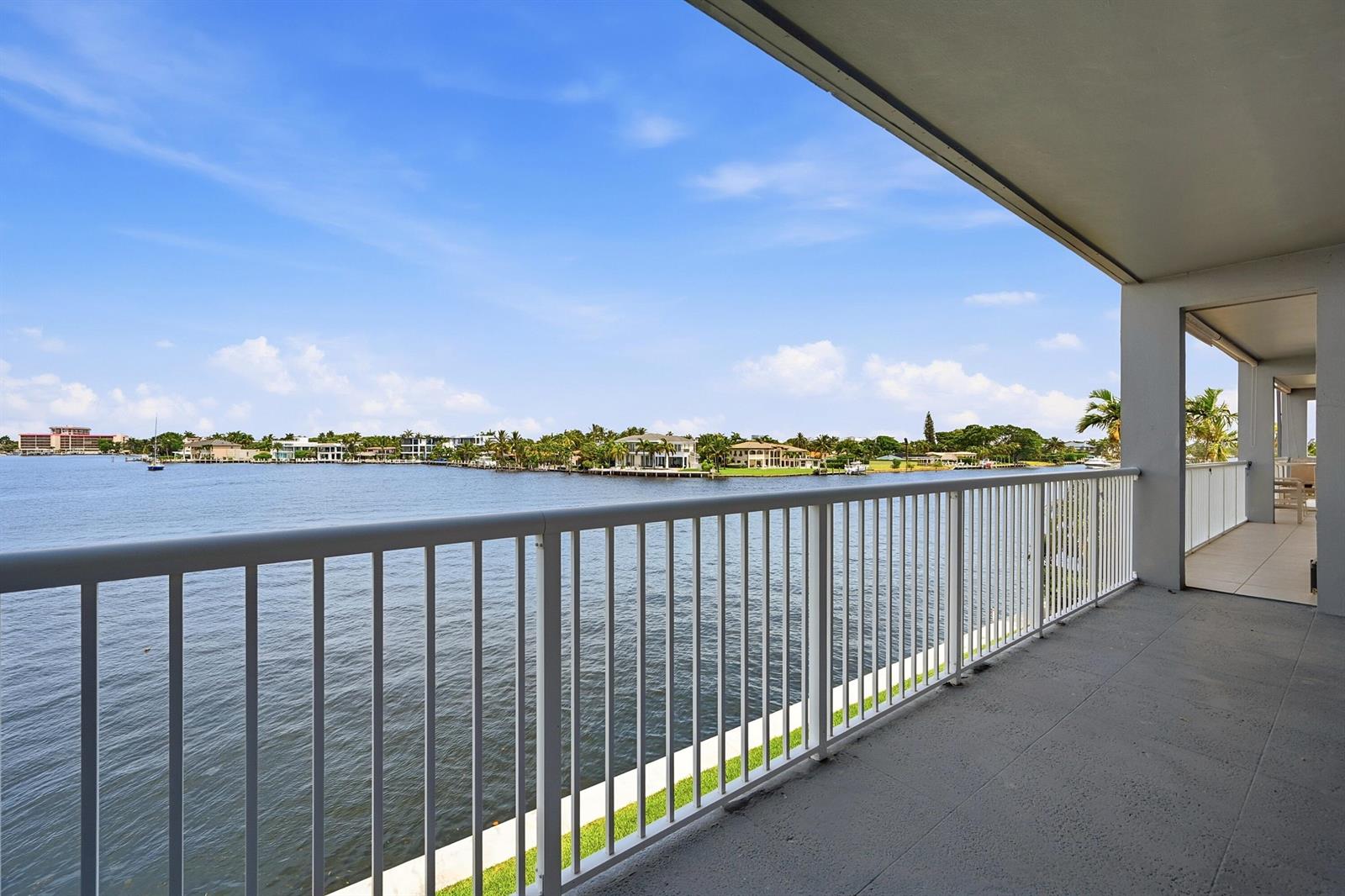 A balcony with a white railing overlooks a wide body of water and distant homes — 1201 S Riverside Drive # 306, Pompano Beach FL 33062, POMPANO BEACH, FL