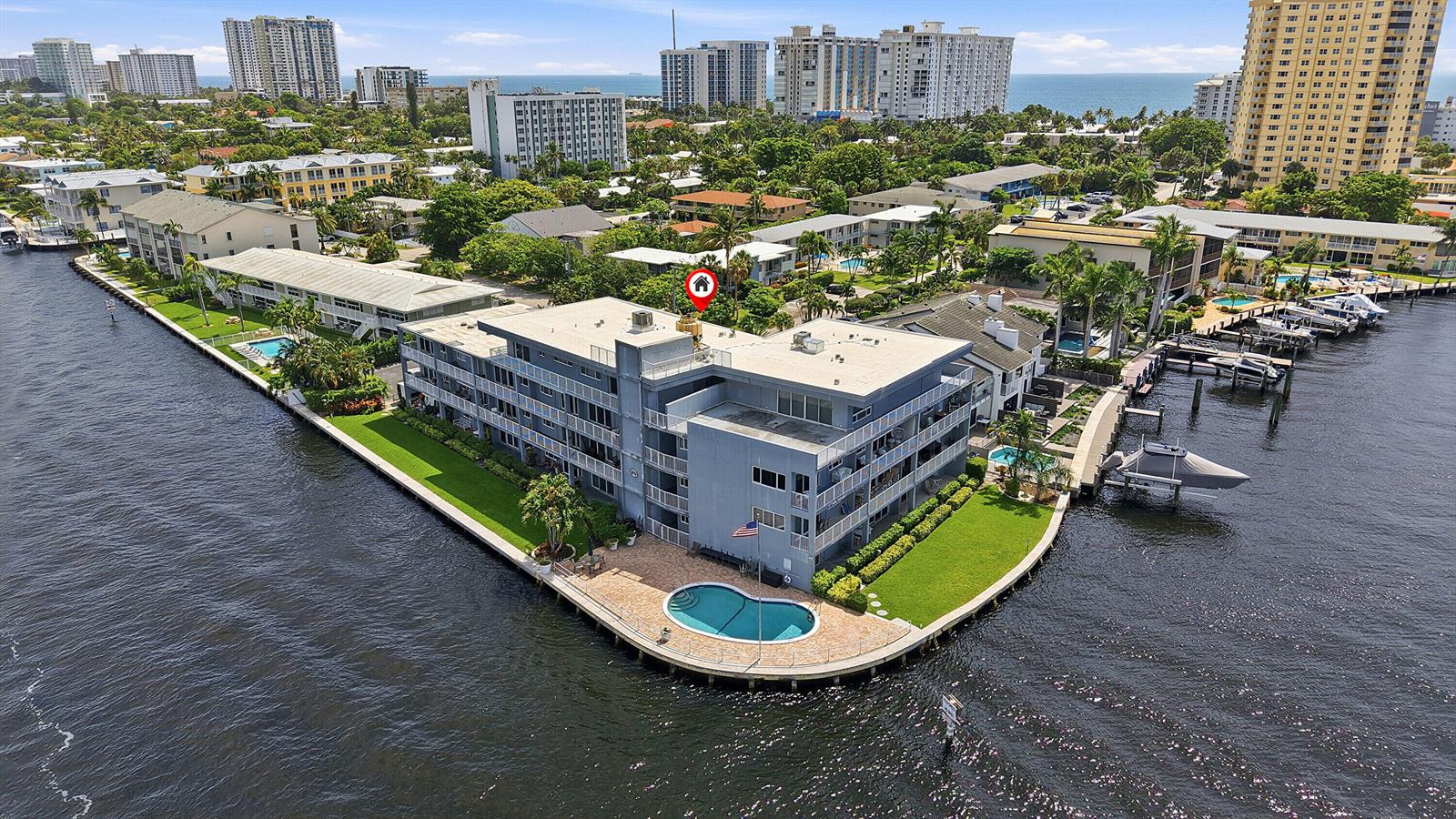 An aerial view of a waterfront apartment building with a pool and boat docks — 1201 S Riverside Drive # 306, Pompano Beach FL 33062, POMPANO BEACH, FL