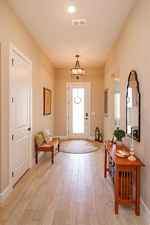 A bright entryway features light wood-look tile flooring, a wooden bench, and a console table — 5663 SW 92ND AVENUE ROAD, OCALA, FL