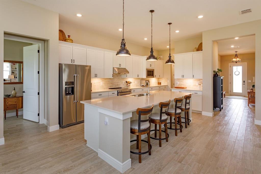 A kitchen with white cabinets, stainless steel appliances, a large island, and wood-look tile flooring — 5663 SW 92ND AVENUE ROAD, OCALA, FL