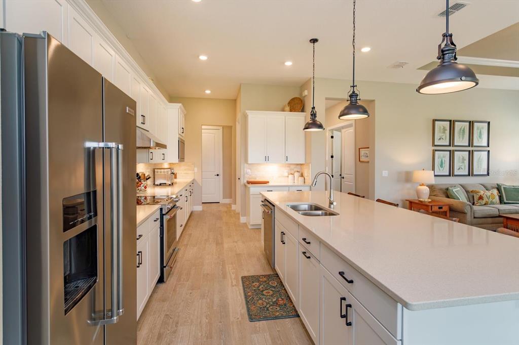 A modern kitchen features white cabinetry, stainless steel appliances, and a large quartz-topped island — 5663 SW 92ND AVENUE ROAD, OCALA, FL