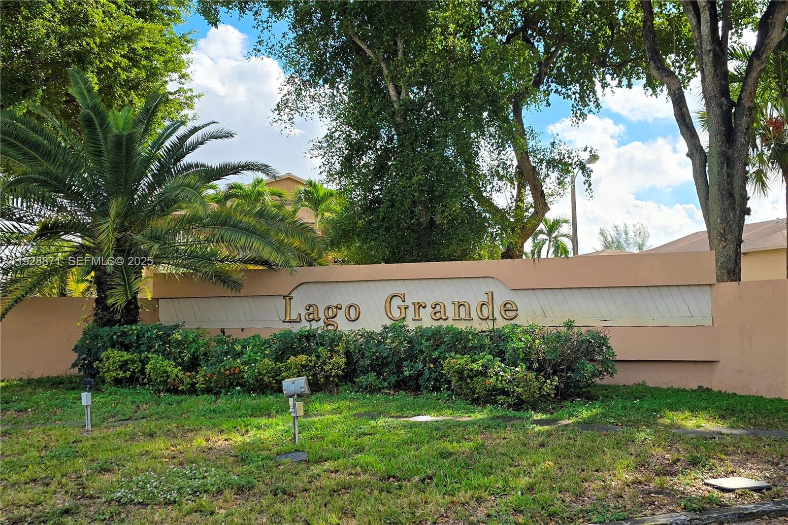 A beige stucco sign with the text Lago Grande stands in front of lush landscaping — 6580 W 27th Ct # 21, Hialeah FL 33016, HIALEAH, FL
