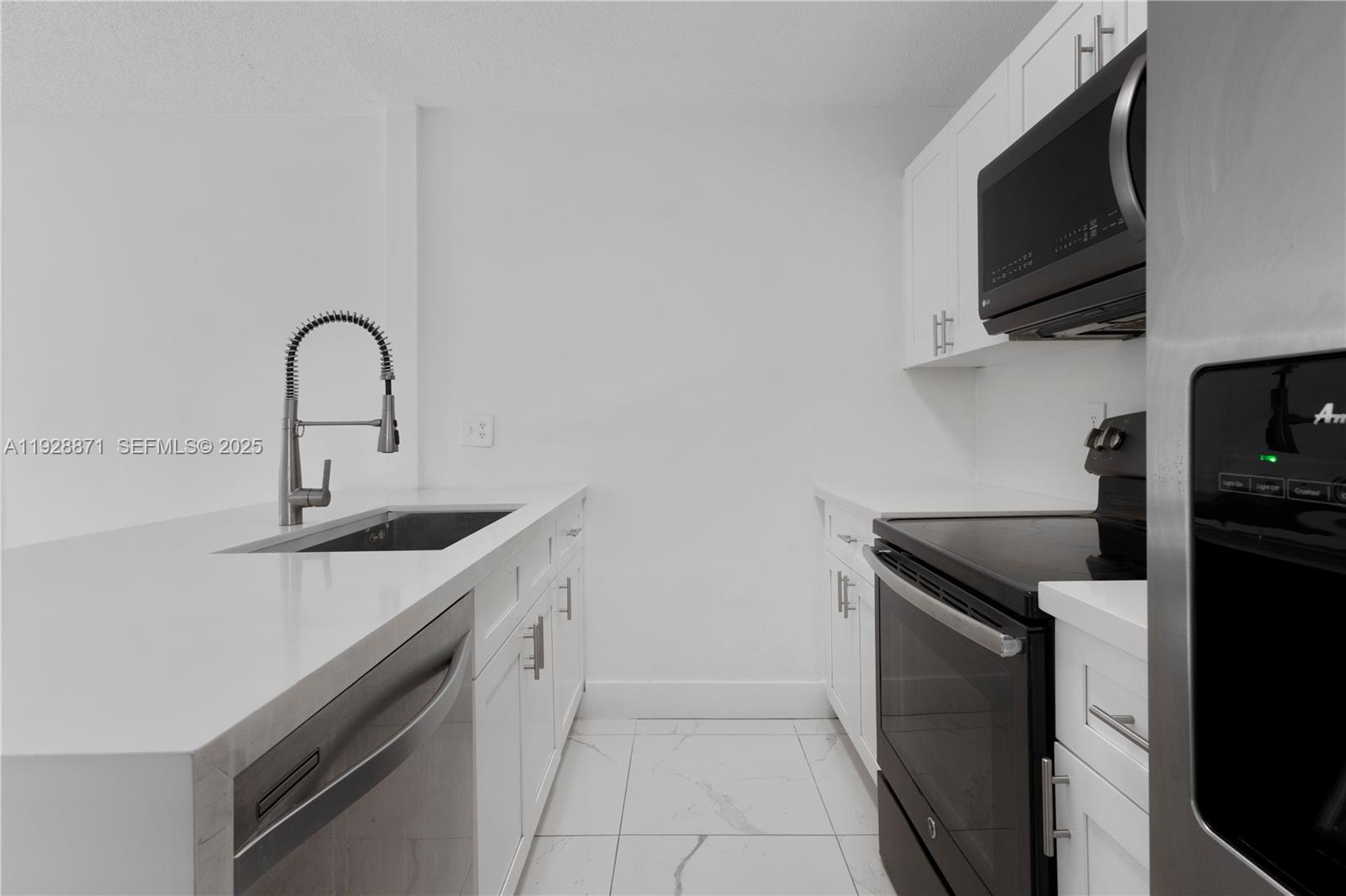 A modern kitchen features white cabinets, white countertops, stainless steel appliances, and tiled flooring — 6580 W 27th Ct # 21, Hialeah FL 33016, HIALEAH, FL