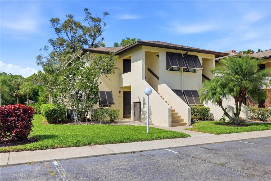 A two-story stucco apartment building features an exterior staircase and dark brown window shutters — 4528 LONGWATER UNIT 35, SARASOTA, FL