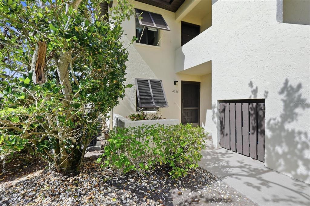 An exterior view of a two-story building entrance with a small patio and landscaping — 4528 LONGWATER UNIT 35, SARASOTA, FL