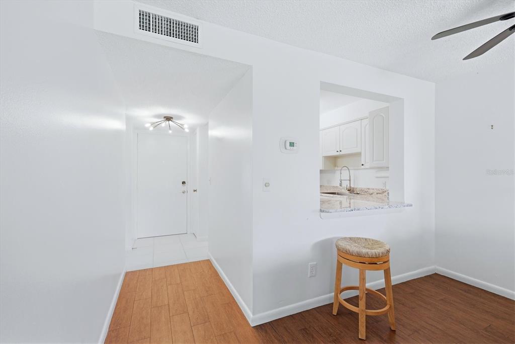 A view of an entryway and kitchen pass-through window with wood-look flooring and white walls — 4528 LONGWATER UNIT 35, SARASOTA, FL