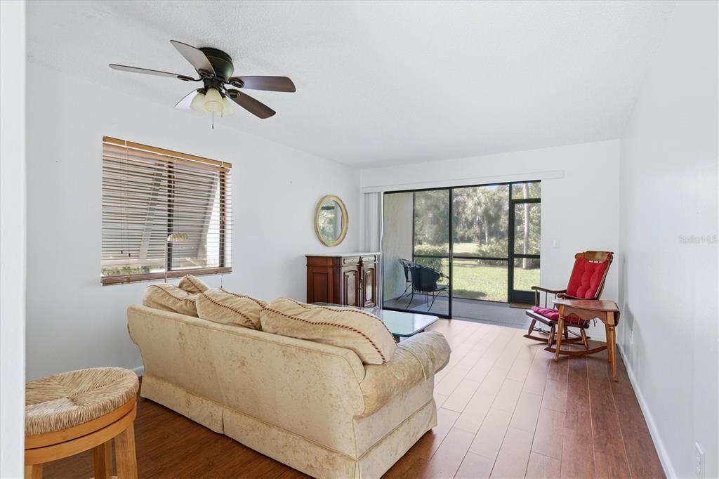 A living room features a beige sofa, a rocking chair, wood flooring, and a sliding door — 4528 LONGWATER UNIT 35, SARASOTA, FL