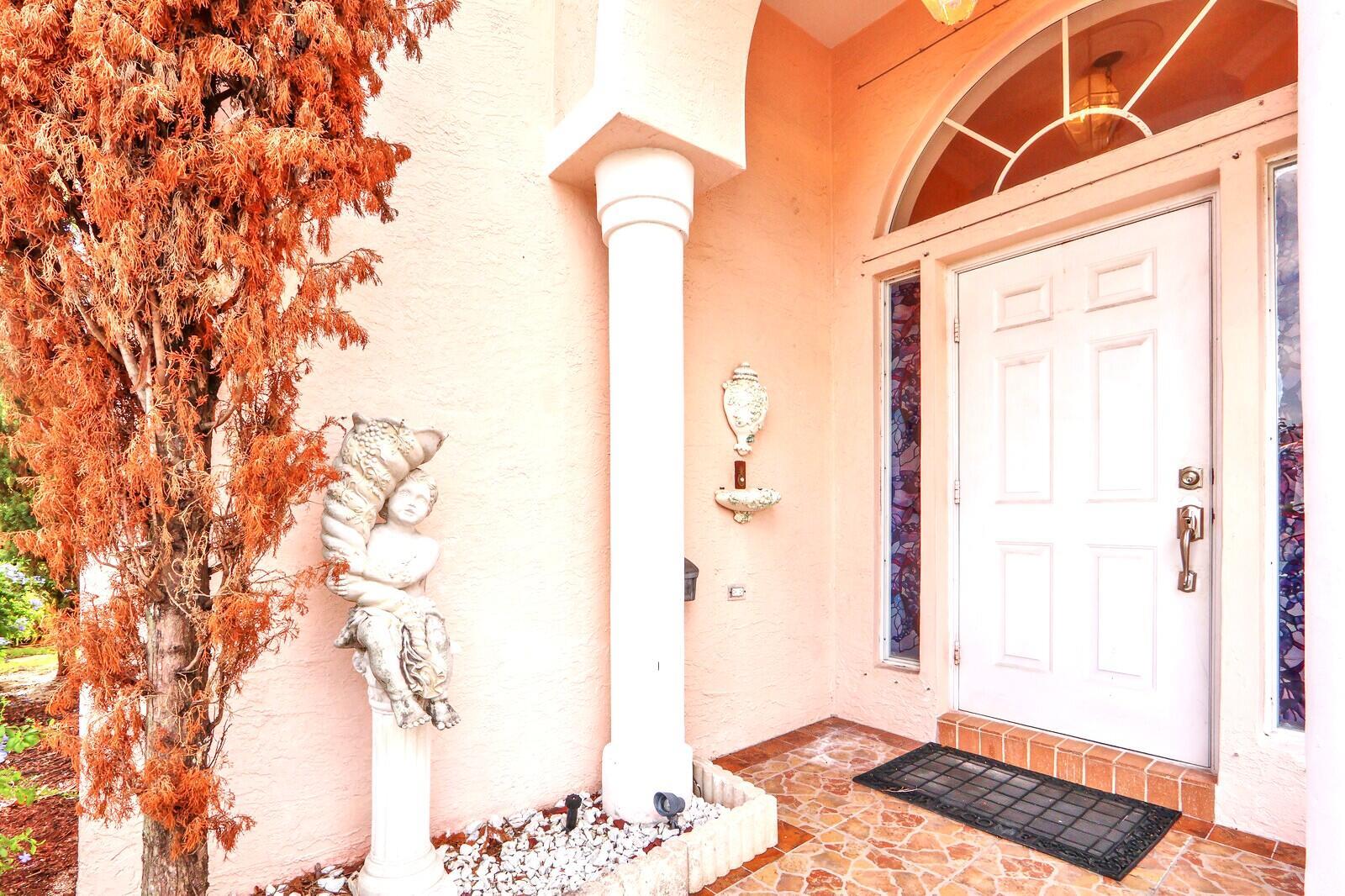 A white front door with sidelights and a decorative statue on a peach-colored porch — 3167 El Camino, West Palm Beach FL 33409, WEST PALM BEACH, FL