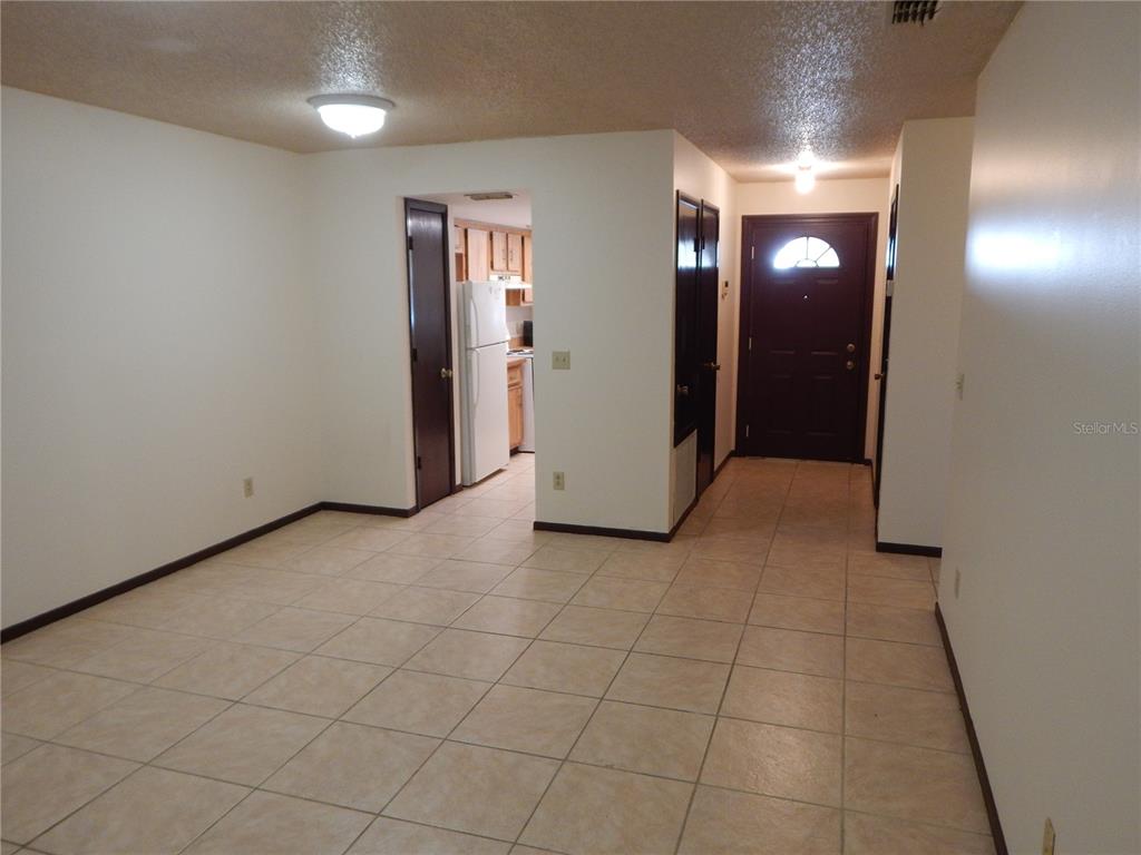 An interior view shows a tiled living area leading to a kitchen and front door — 2505 CORAL AVENUE, KISSIMMEE, FL