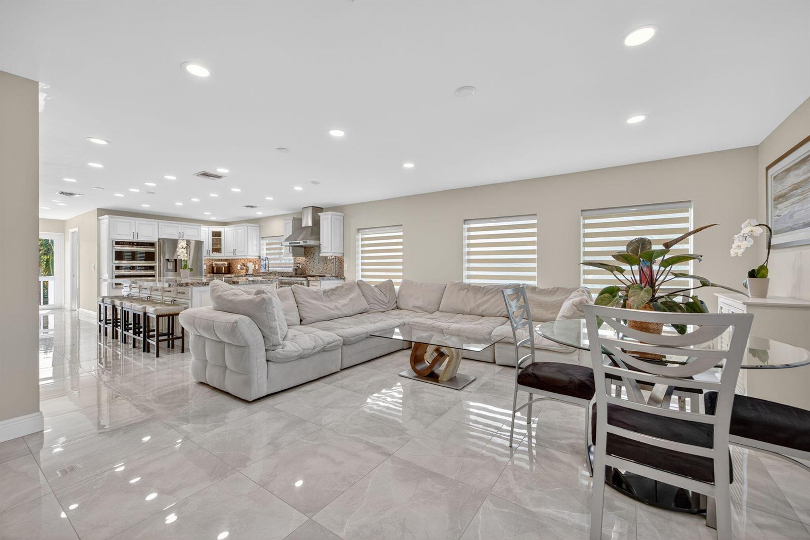 An open-concept living room and kitchen featuring white cabinetry, a sectional sofa, and tiled floors — 27385 Saint Lucie Lane, FL 33042, FL