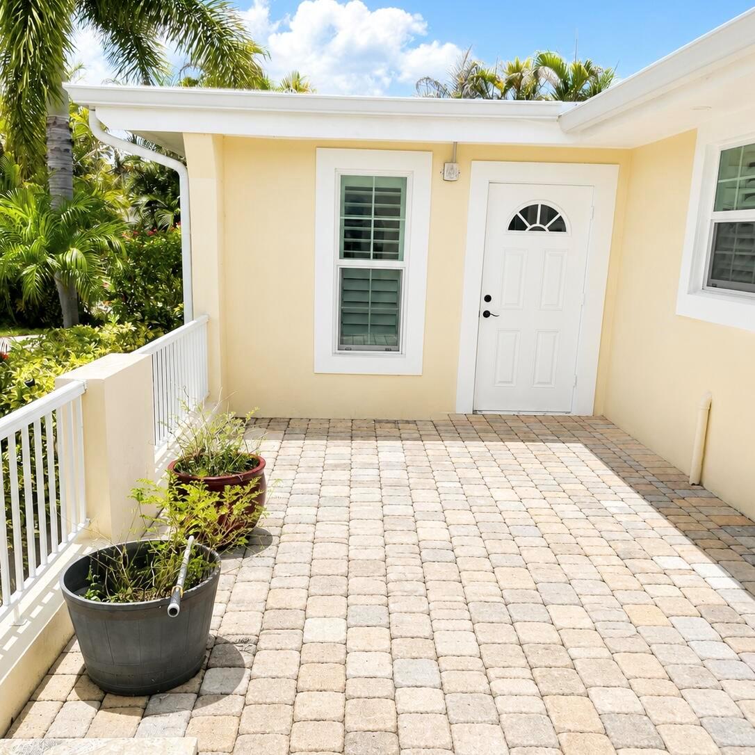 A paved patio area features a white door, a window, and potted plants — 1023 NW SPRUCE RIDGE Drive, Stuart FL 34994, STUART, FL