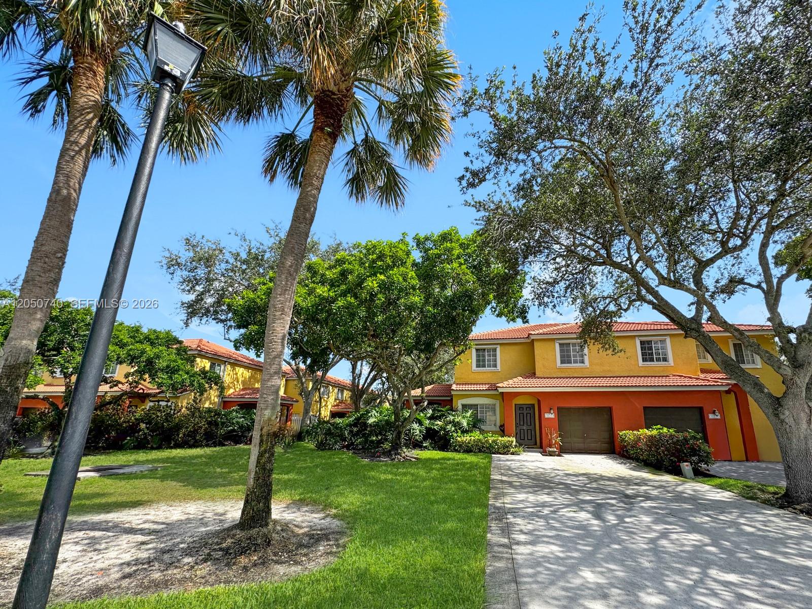 A two-story yellow and orange townhouse with a driveway and palm trees — 10341 SW 18th St, Miramar FL 33025, MIRAMAR, FL
