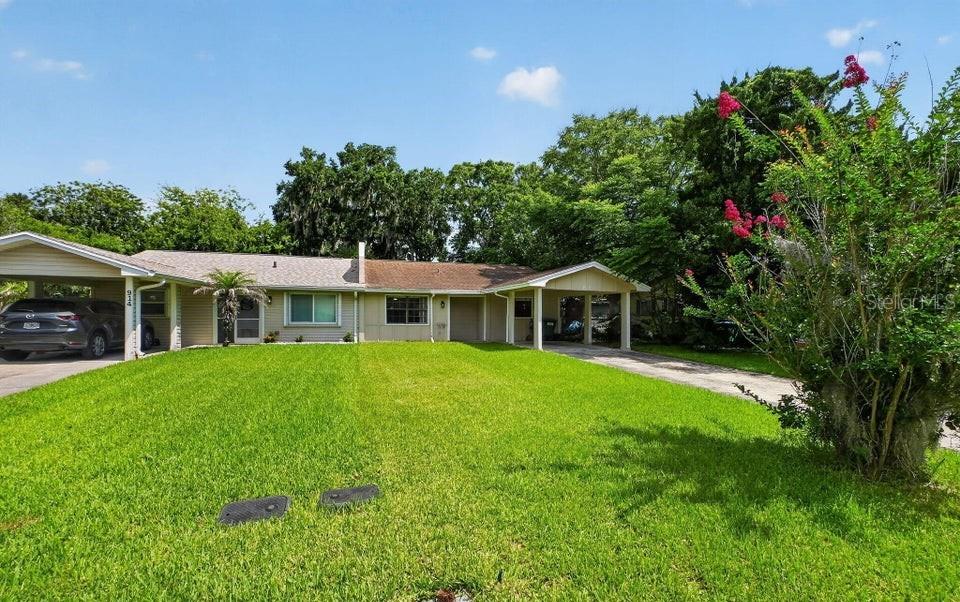 A single-story house with a carport and a large front lawn under a blue sky — 912 ROYAL OAK COURT, HOLLY HILL, FL