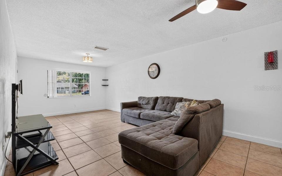 A living room features a brown sectional sofa, tile flooring, and a ceiling fan — 912 ROYAL OAK COURT, HOLLY HILL, FL
