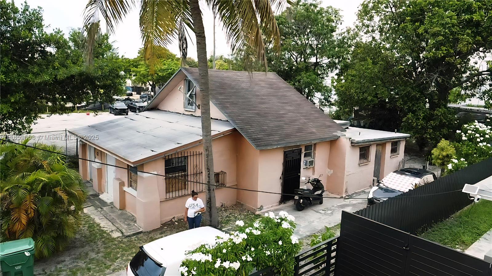 An exterior view of a single-story pink house with a dark roof and a palm tree — 683 NW 30th St, Miami FL 33127, MIAMI, FL