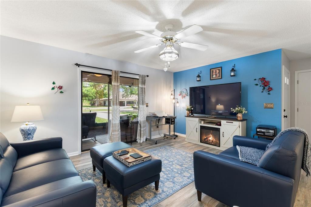 A living room features blue walls, a fireplace console, leather furniture, and a sliding glass door — 302 GENESIS POINTE DRIVE, LAKE WALES, FL