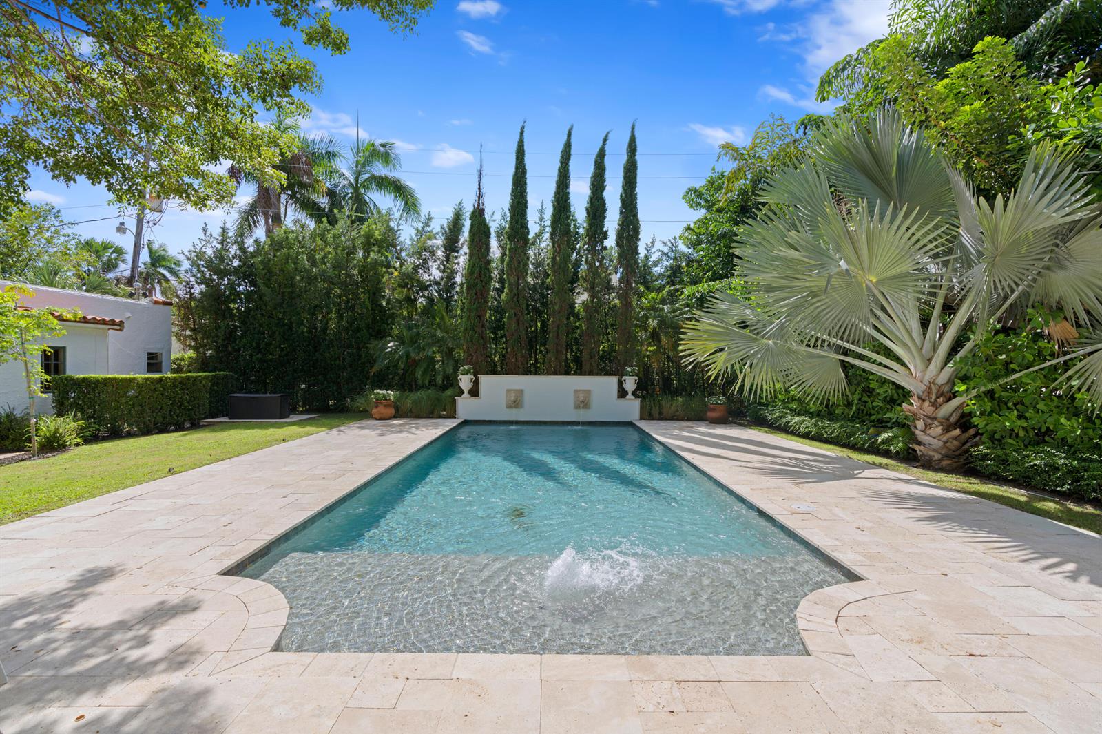 A rectangular swimming pool with a sun shelf and fountain sits in a landscaped backyard — 308 BARCELONA Road, West Palm Beach FL 33401, WEST PALM BEACH, FL