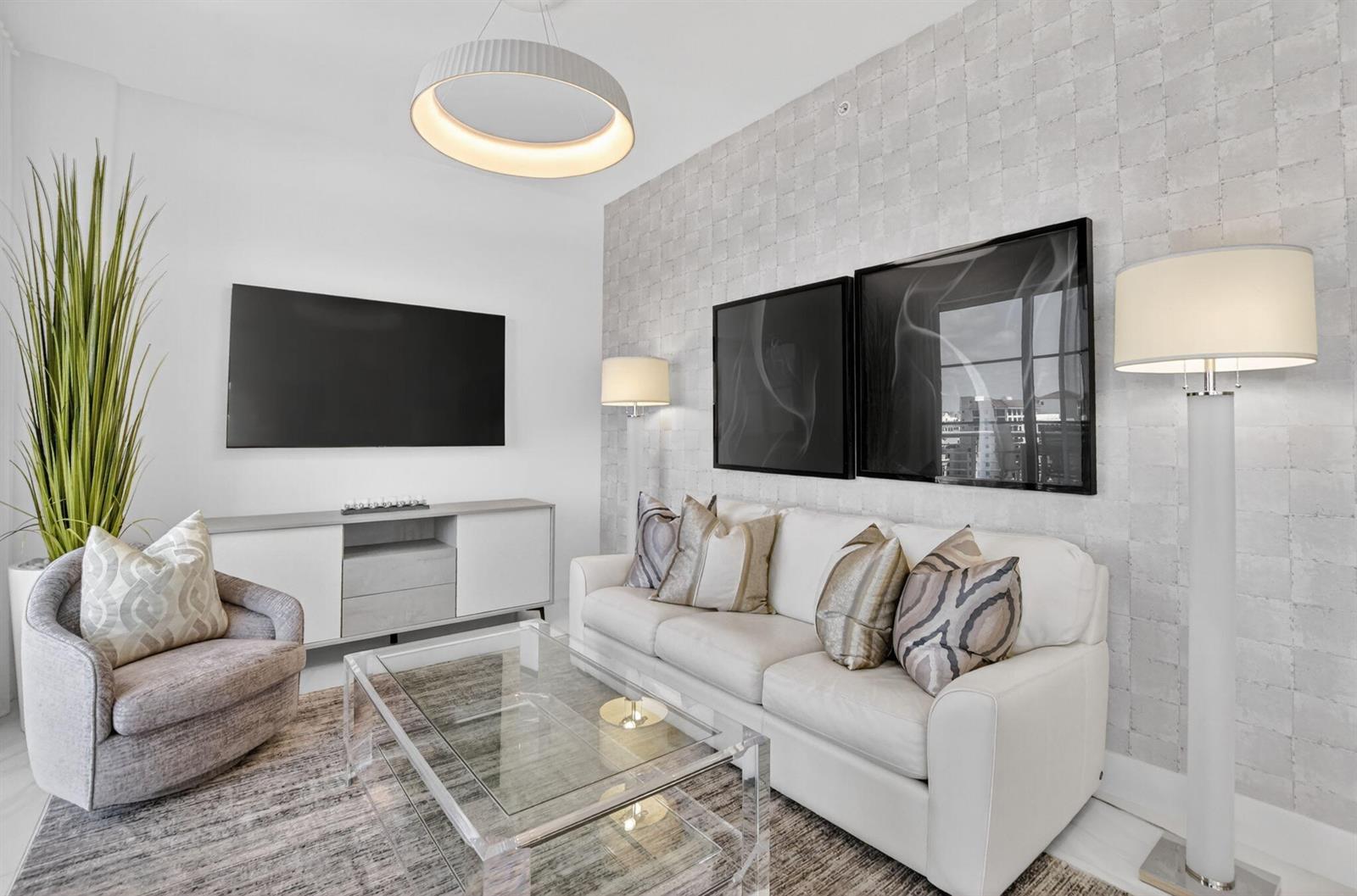 A modern living room features a white sofa, glass coffee table, and textured accent wall — 155 E Boca Raton Road # 1201, Boca Raton FL 33432, BOCA RATON, FL