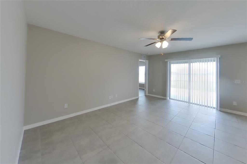 An empty living room features light gray tile flooring, neutral walls, and a ceiling fan — 2163 MANDARIN LOOP, DUNDEE, FL