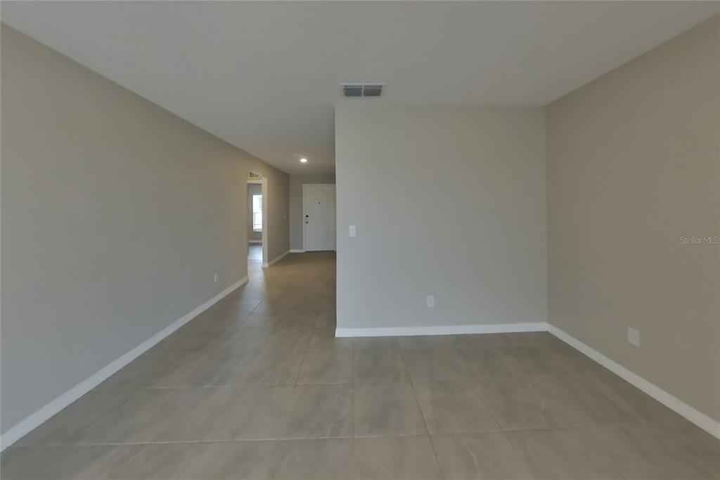 An empty room with light-colored tile flooring and neutral walls leads to an entryway — 2163 MANDARIN LOOP, DUNDEE, FL