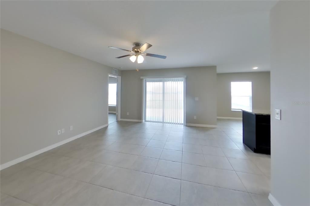 An open-concept living area features light gray tile flooring, neutral walls, and a ceiling fan — 2163 MANDARIN LOOP, DUNDEE, FL