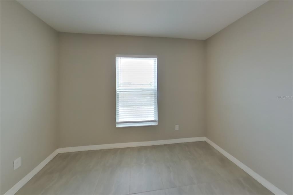 An empty room with light gray walls, white trim, and light-colored tile flooring — 2163 MANDARIN LOOP, DUNDEE, FL