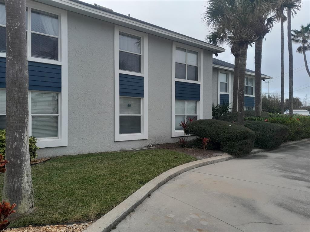 A two-story building with gray stucco walls, blue accents, and white-framed windows — 4860 S ATLANTIC AVENUE UNIT 201, NEW SMYRNA BEACH, FL