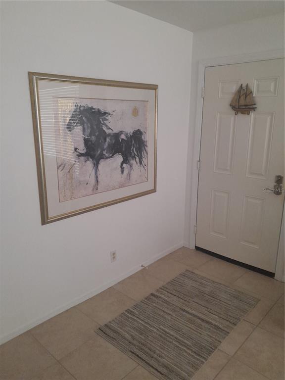 An entryway features tile flooring, a framed horse painting on the wall, and a white door — 4860 S ATLANTIC AVENUE UNIT 201, NEW SMYRNA BEACH, FL