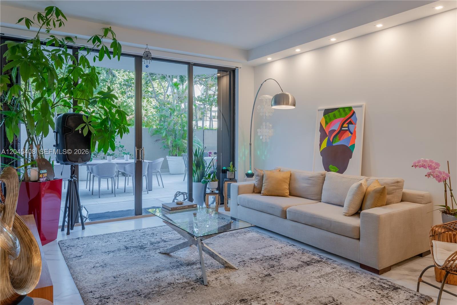 A living room features a beige sofa, glass coffee table, and sliding doors to a patio — 151 Crandon Blvd # 122, Key Biscayne FL 33149, KEY BISCAYNE, FL
