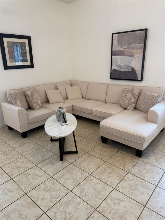 A beige sectional sofa sits on a tiled floor in a room with two wall paintings — 4573 ADA LANE, KISSIMMEE, FL