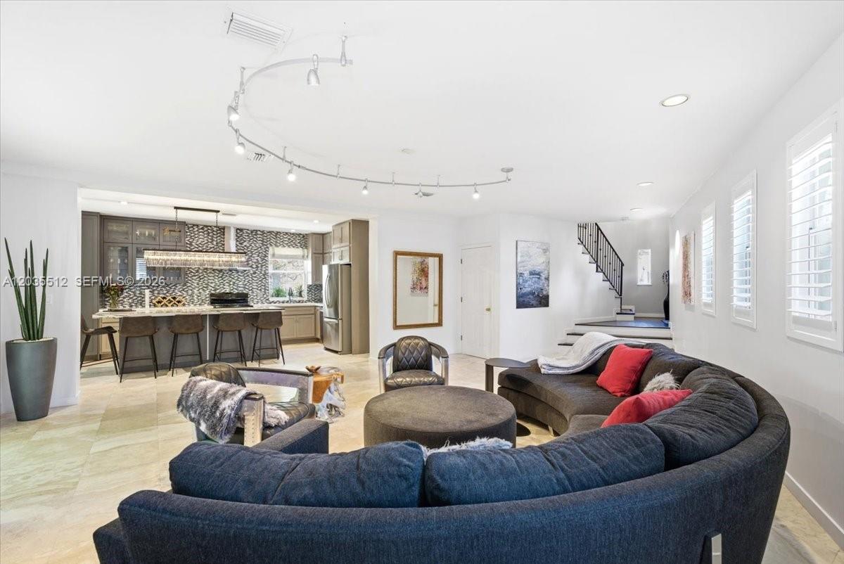 A living room with a curved sofa and kitchen area featuring a breakfast bar — 2917 Jackson Ave, Miami FL 33133, MIAMI, FL