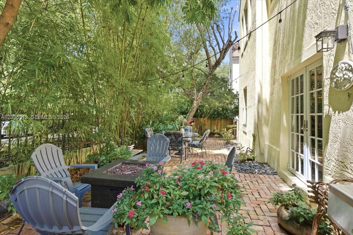 A brick patio features a fire pit, Adirondack chairs, and bamboo landscaping beside a house — 2917 Jackson Ave, Miami FL 33133, MIAMI, FL